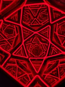 Vibrant red neon geometric star sculpture with intricate interconnected patterns, modern art piece for interior or exterior decor.