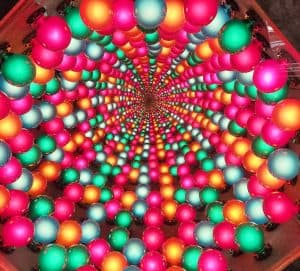 Colorful Christmas ornament balls in vibrant shades of pink, green, orange, and silver arranged in a spiral pattern.