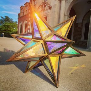 Colorful stained glass star lantern outdoors during sunset.