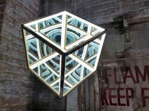 LED illuminated geometric mirror cube art installation.