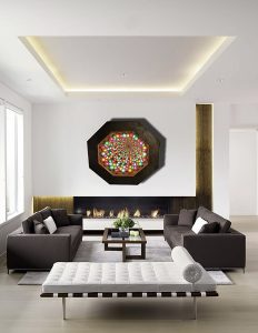 Colorful modern wall art above sleek fireplace in contemporary living room.