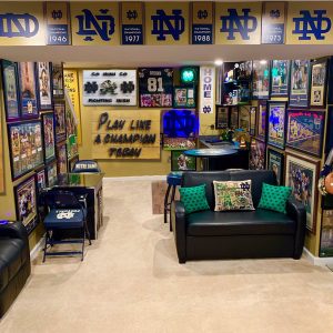 Vintage Notre Dame Fighting Irish sports memorabilia collection room with framed photos, jerseys, and themed decor.